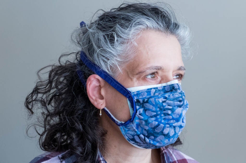 A woman wears a cloth mask on top of a surgical mask.