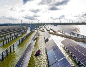 Electrical workers check solar panels at a photovoltaic power station built in a fishpond in Haian in China's eastern Jiangsu province. (STR/AFP via Getty Images)