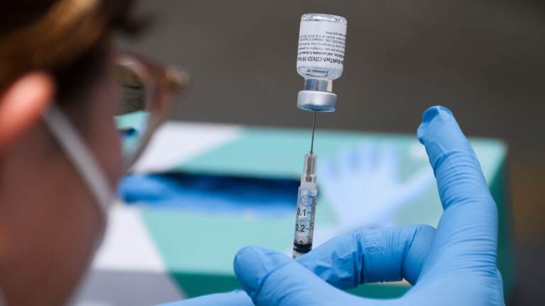 A syringe is filled with a first dose of the Pfizer COVID-19 vaccine
