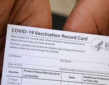 A health care worker displays a COVID-19 vaccination record card