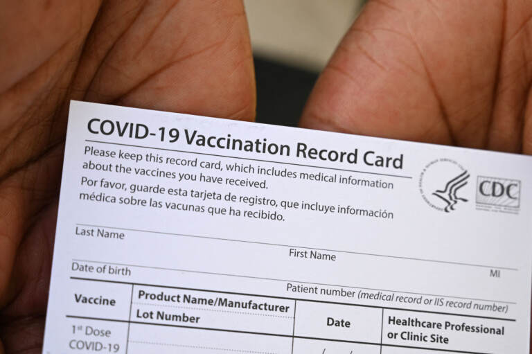 A health care worker displays a COVID-19 vaccination record card