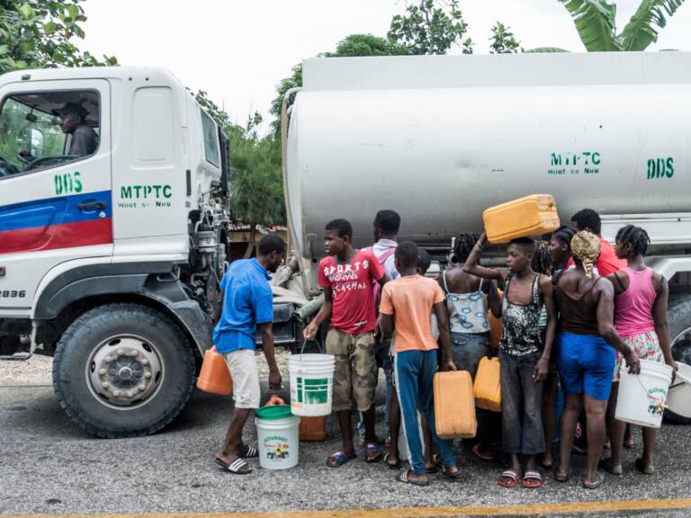 People gather near bins of water after the earthquake in Camp-Perrin