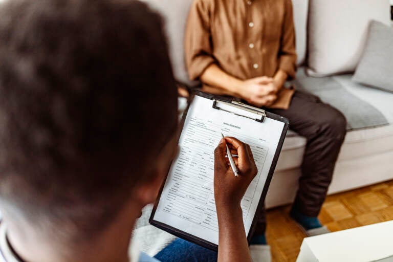 A psychologist is pictured writing notes during a therapy session with a patient