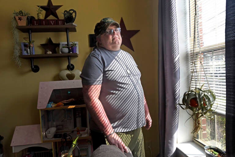 In Camden on August 6, Antioch Manor resident Don Brown stands at the window in his apartment; from it, he watched a murder take place earlier this year. (April Saul for WHYY)