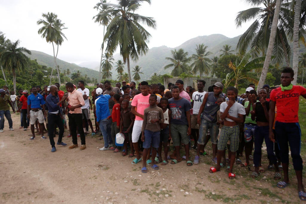 Families wait to receive humanitarian aid from a U.S. Army helicopter unit