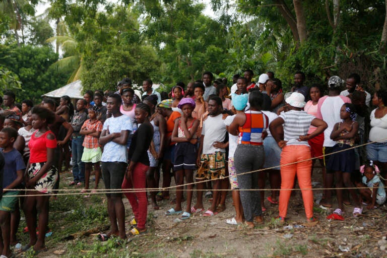 Families wait to receive humanitarian aid from a U.S. Army helicopter unit