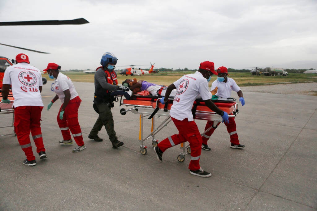 The U.S. Coast Guard and the Haitian Red Cross transport a patient to a tent hospital