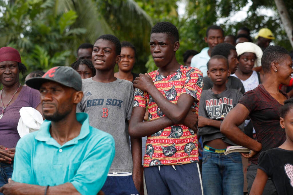 Families wait to receive humanitarian aid from a U.S. Army helicopter