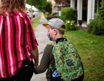 A parent hold their kids hand on their way to school.