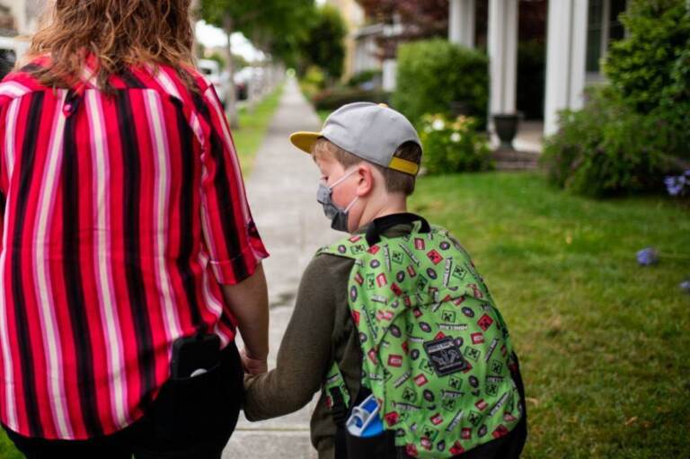 A parent hold their kids hand on their way to school.