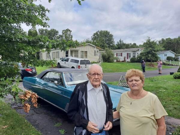 Tom Watts Sr. and Carol Ryan stand in front of a car in the driveway