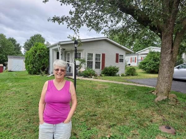 Kathie Sessinger stands in front of her home