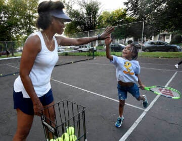 Kelly Cass-White gets a high-five from tennis student Harlem Lewis, 6 on Aug. 26, 2021