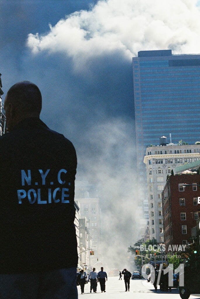 World Trade Center Building Seven, on the right, hours before it collapsed with dust and smoke pouring past it into the streets of Lower Manhattan following the collapse of the Twin Towers