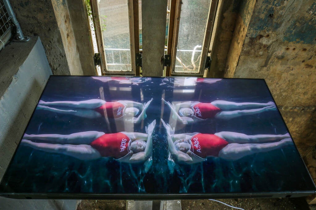 A video screen shows swimmers in the water