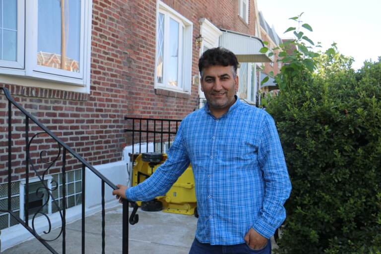 Mohammed Sadeed stands with his hand on a railing outside his home