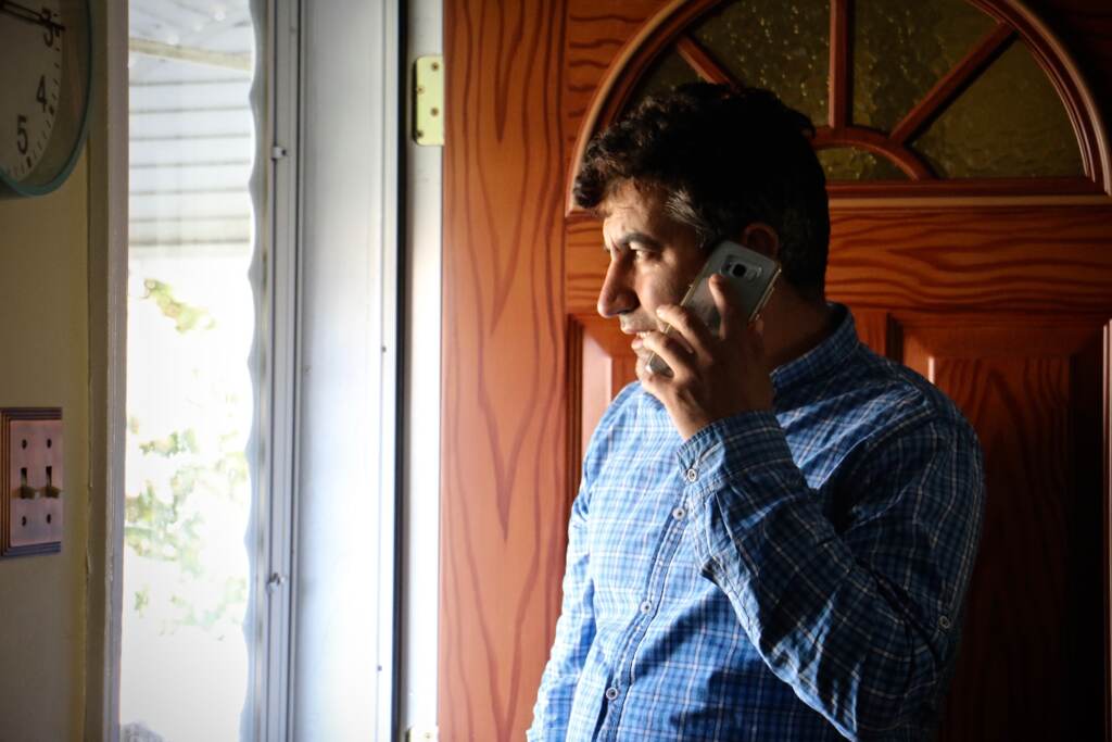 Mohammed Sadeed holds a phone to his ear as he stands by his front door