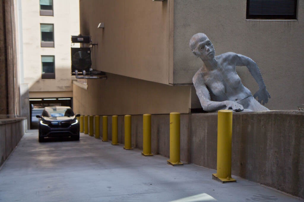 A driver enters the parking garage on 13th and Cuthbert streets, where a statue is pictured