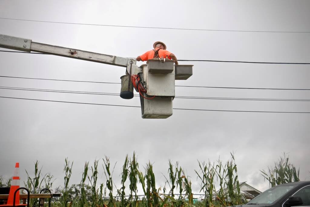 A utility worker repairs wires at Wellacrest Farms