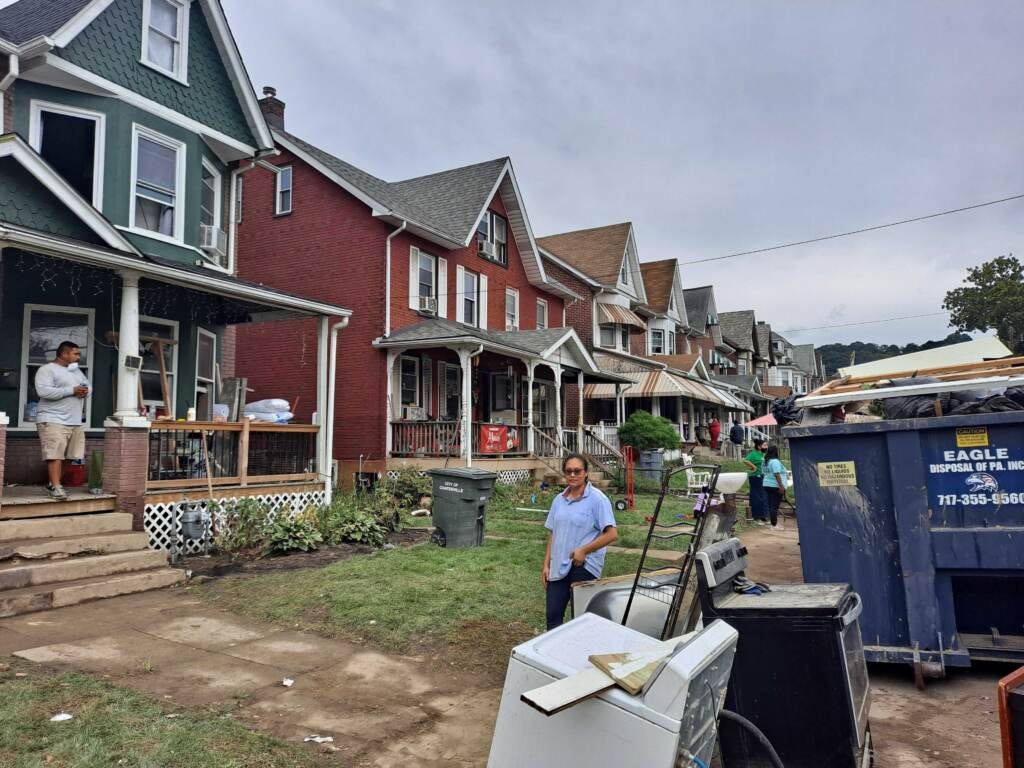 Person stands in front of house after flood.