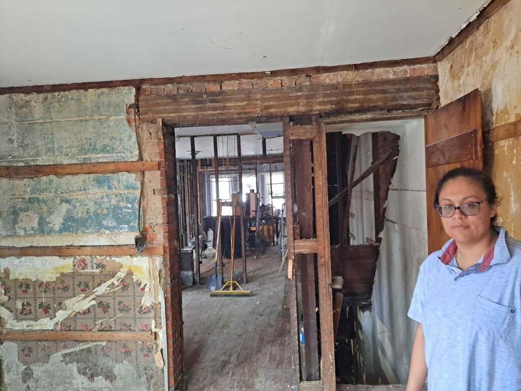 Person stands in damaged house.