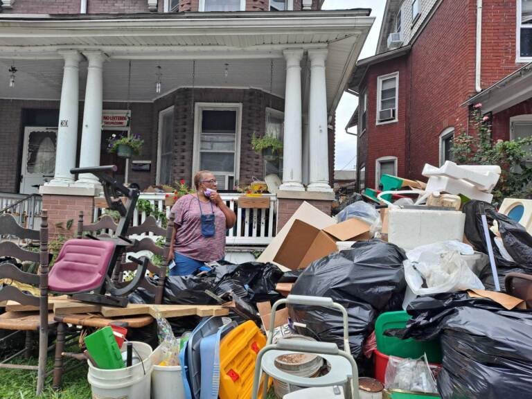 Person stands in front of house damaged by hurricane flooding.