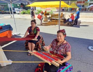 Two people showcase Guatemalan weaving.