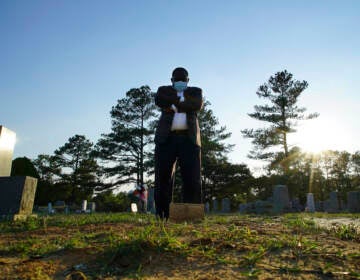 Mortician stands at a grave.