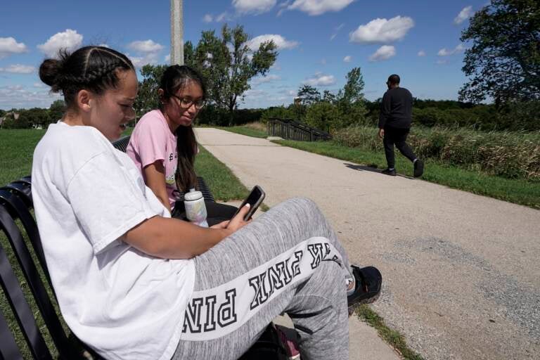 Two girls sit on bench