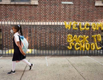 FILE - In this Sept. 13, 2021, file photo, a girl passes a 'Welcome Back to School' sign as she arrives for the first day of class. (AP Photo/Mark Lennihan, File)