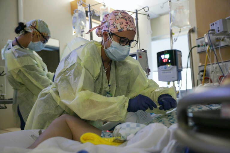 A critical care nurse administers an anti-viral medication to a COVID-positive patien