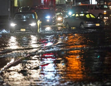 Cars make their way through flooded streets and around abandoned cars in Teterboro