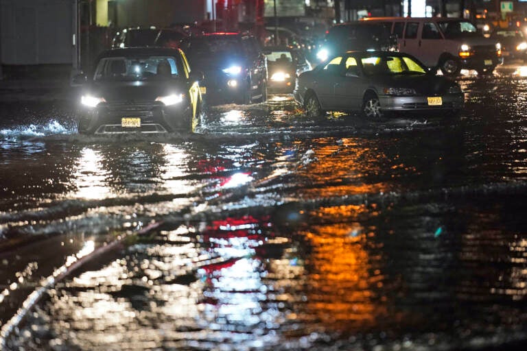 Cars make their way through flooded streets and around abandoned cars in Teterboro