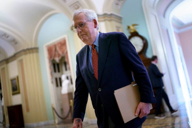 Senate Minority Leader Mitch McConnell walks while holding a folder