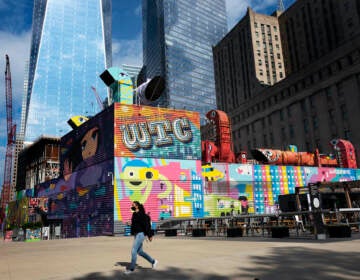 A woman walks by the colorful murals that surround the foundation for 2 World Trade Center