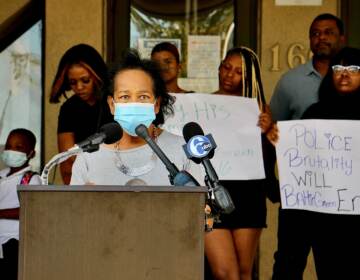 Zulene Mayfield, wearing a mask, speaks at a press conference