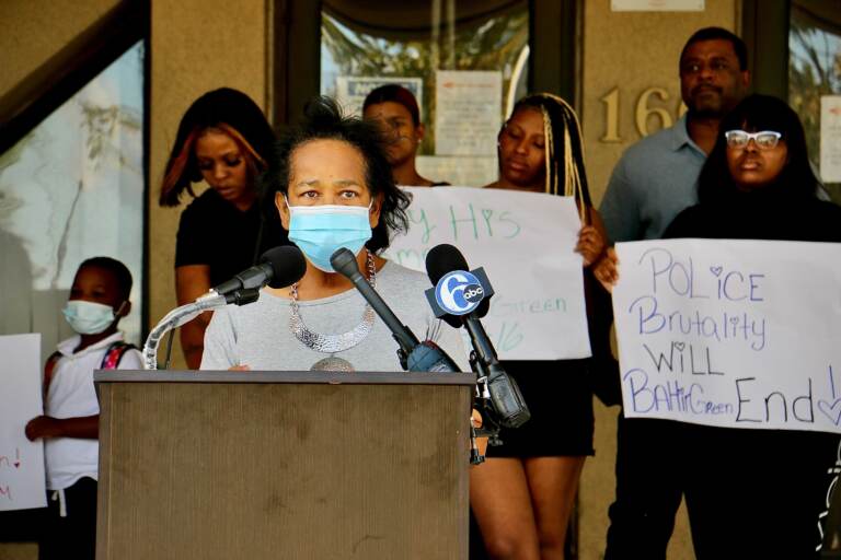 Zulene Mayfield, wearing a mask, speaks at a press conference