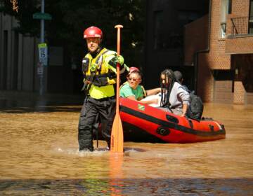 Philadelphia Fire Department personnel carry residents of the River Walk apartments to dry land