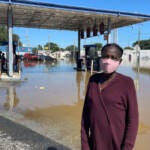 Andrienne Dolley stands in front of a gas station whose lot was left submerged by Ida's remnants. (Cris Barrish/WHYY)