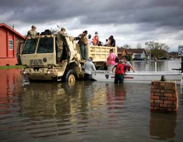 First responders drive a high water vehicle through flooded streets while rescuing residents