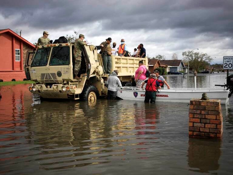 First responders drive a high water vehicle through flooded streets while rescuing residents