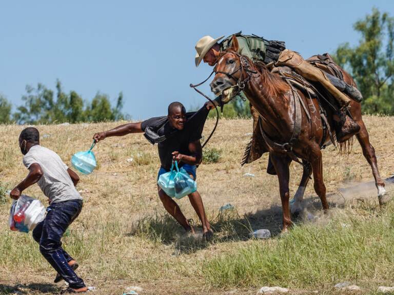 A U.S. Border Patrol agent on horseback tries to stop a Haitian migrant from entering an encampment on the banks of the Rio Grande