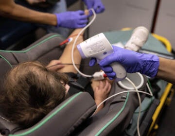 A medic takes the temperature of a 2-year-old sitting in a car seat