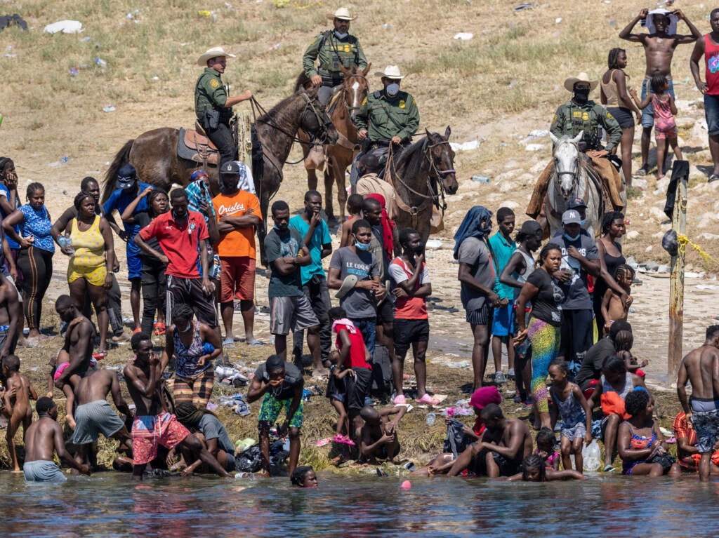 Mounted Border Patrol agents watch Haitian immigrants on the bank of the Rio Grande in Del Rio