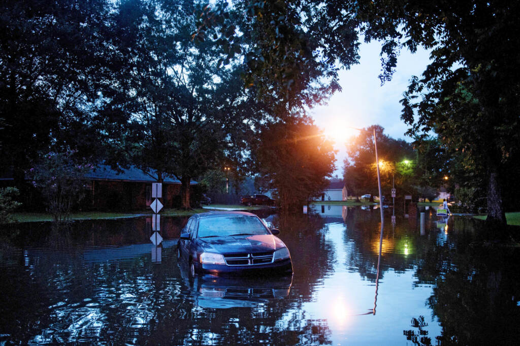 An abandoned car is seen in a flooded street