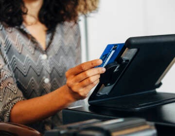 A cashier swipes a credit card at a register.