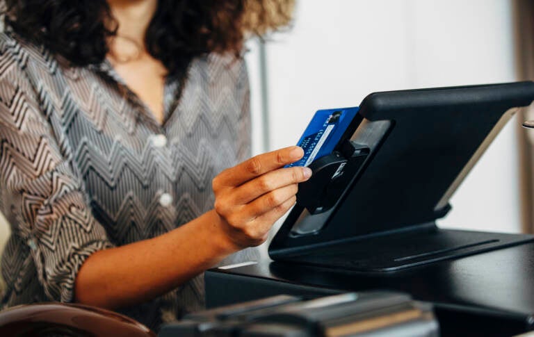 A cashier swipes a credit card at a register.