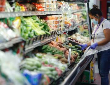 A woman wears a mask while shopping the produce section