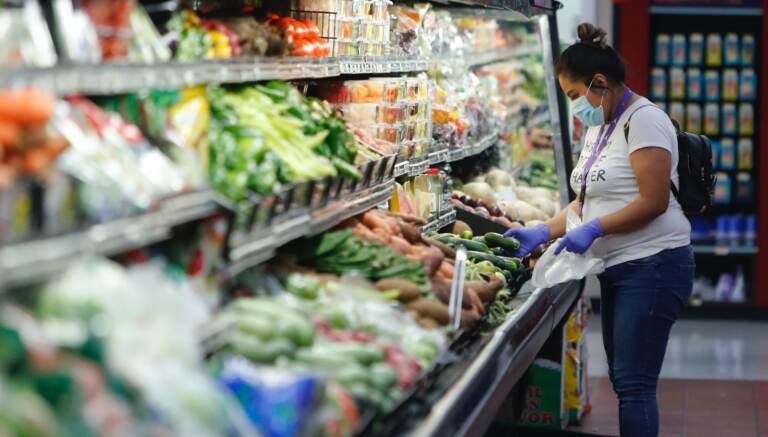 A woman wears a mask while shopping the produce section