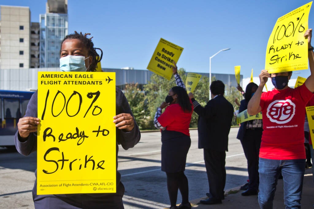 Keturah Johnson holds up a yellow sign at a protest outside PHL Airport